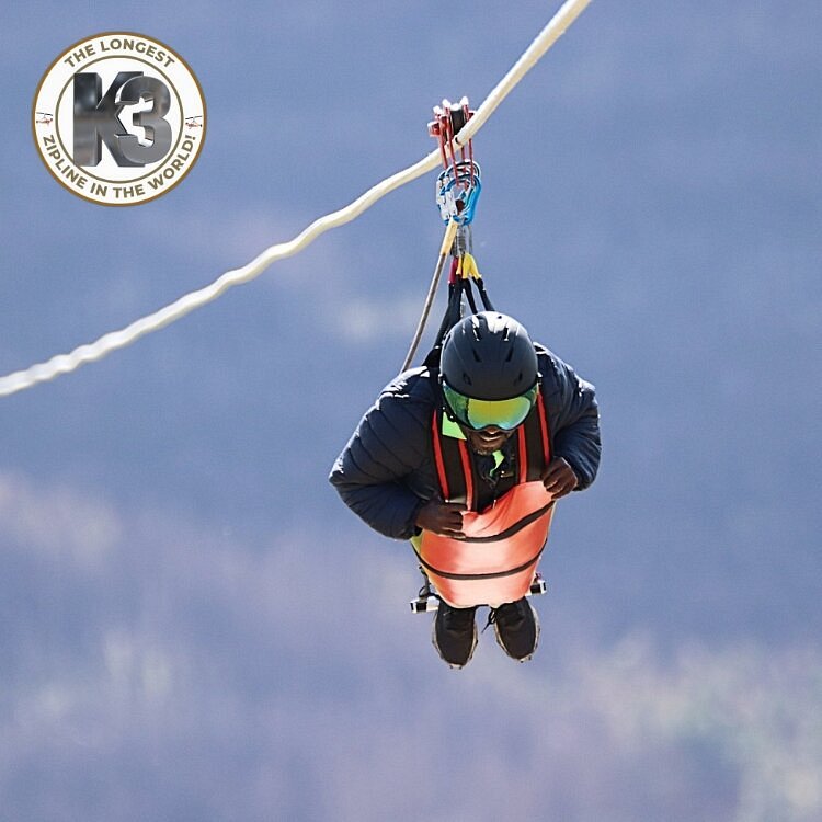 Person strapped into the K3 zipline in a harness where they're facing the ground