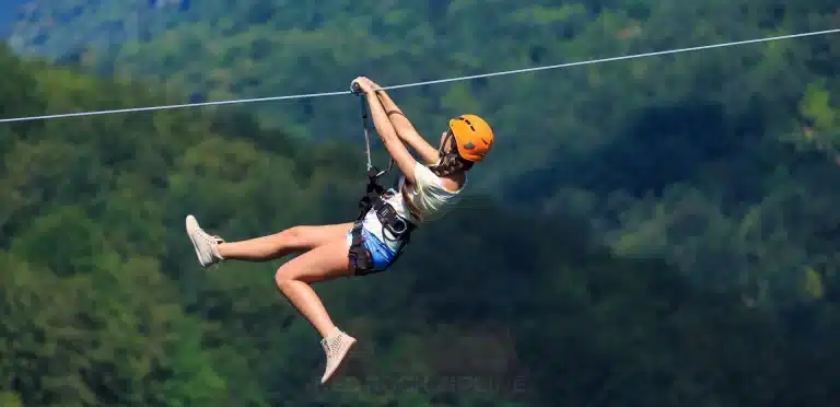Woman rides down Volo dell’ Angelo Zipline, with her hands on the ziplines handle to control the speed